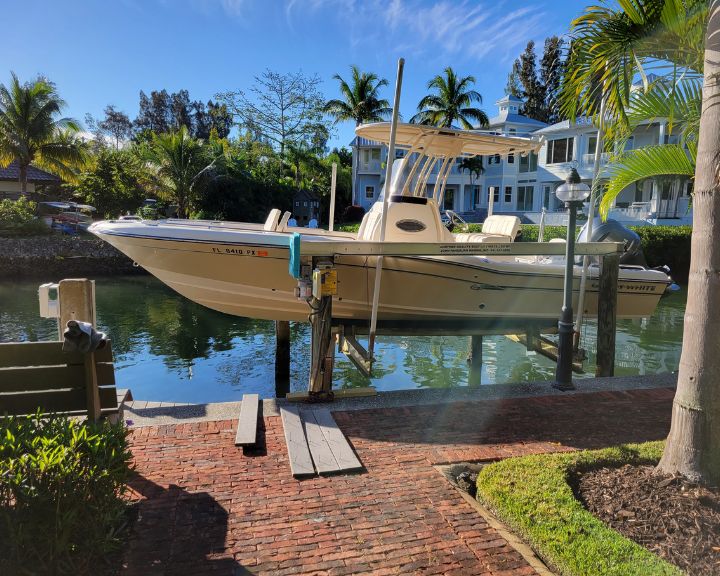 A boat docked on a boat lift in front of a house.