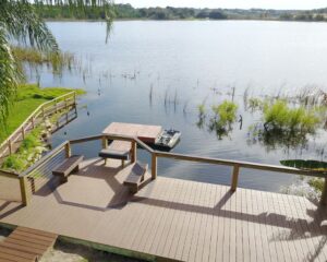 A wooden deck overlooking a lake with palm trees, constructed by Orlando Dock Builders.
