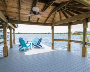 A wooden deck with blue chairs and a view of the water, built by Orlando Dock Builders.