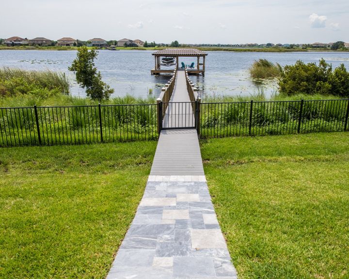 Orlando Dock Builders have created a picturesque walkway leading to a serene dock on a lake.