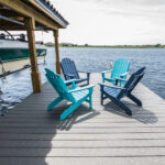 Four chairs on a dock next to a boat.