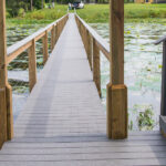 A wooden bridge over a pond with water lilies.