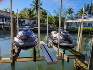 Two jet skis are parked on a dock in the water.