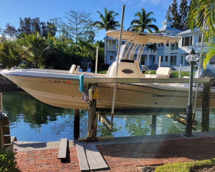 A boat docked using a boat lift at a dock in front of a house in Orlando.